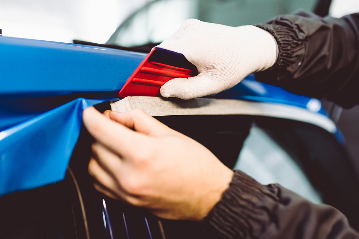 A person is applying a blue vehicle wrap.